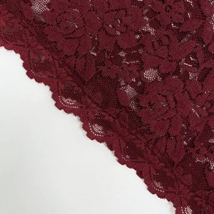 Détail du tissu en dentelle rouge foncé avec broderie de roses et bords festonnés