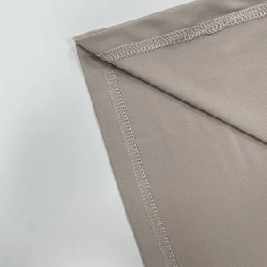 Gros plan détaillé sur la couture overlock professionnelle du tissu en maille taupe