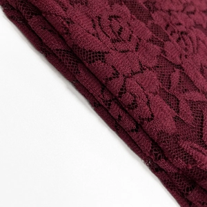 Gros plan sur le tissu en dentelle rouge vin avec motifs de roses et texture en maille