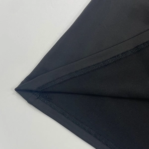 Dettaglio ravvicinato della cucitura a doppio ago sull'orlo del vestito in maglia nera