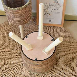 Close-up of woven rattan planter base with sturdy solid wood legs and metal fixings