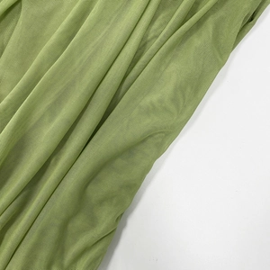 Detailed macro view of the grass green mesh fabric texture with elegant folds and sheer finish