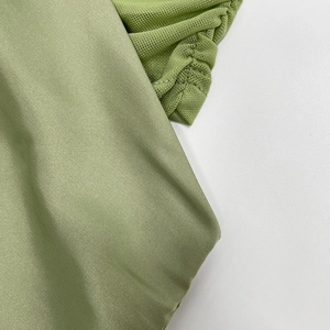Detail of lime green satin fabric joined with semi-transparent mesh stitching