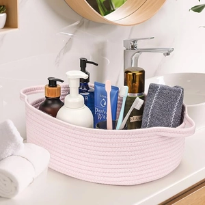 Detail view of pink cotton rope woven storage basket with handles on bathroom counter