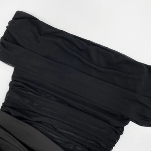 Detail of sheer black mesh dress with elegant ruched textures and layered pleats
