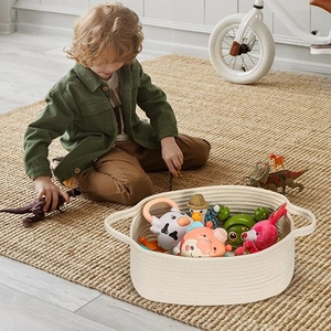 Top view of a woven cotton rope storage basket with handles holding several children toys