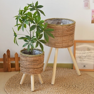 Close-up of two woven plant stands with natural wood legs and plastic liners for drainage