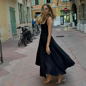 Dynamischer Fluss des schwarzen ärmellosen Maxikleid Saums in einer Straßenszene