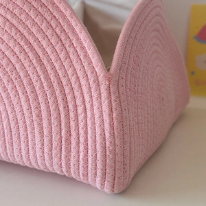 Detail view of pink cotton rope woven basket featuring V-shaped opening and white lining