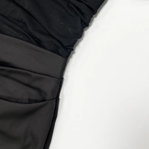 Detail of sheer black mesh and satin fabric with elegant ruched textures and stitching