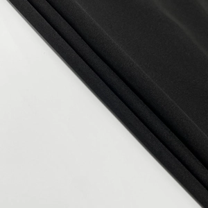 Close-up of black mesh fabric detail with fine texture and subtle drape on the dress