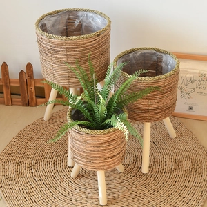 Three-piece set of woven plant stands with wooden legs and protective plastic liners