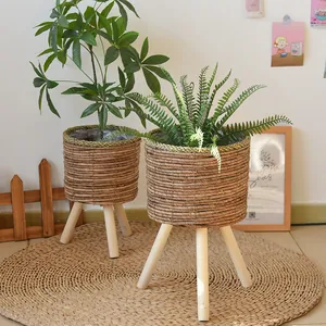 Close-up of two handmade woven grass planters with solid wood legs in a Nordic style