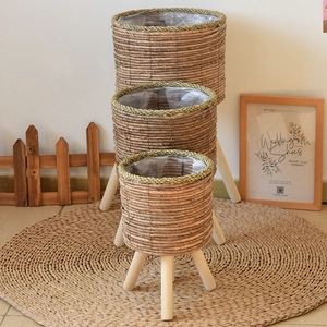 Three-piece set of woven plant stands with natural wood legs and waterproof liners