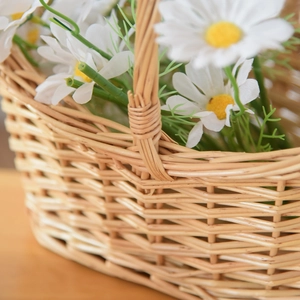 Close-up of a handmade willow flower basket with realistic white daisies and green stems