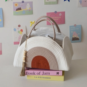 Detail of woven cotton baby diaper caddy featuring a rainbow pattern and tassel charm