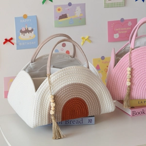 Close-up of woven cotton rope diaper caddy featuring rainbow stripes and wood bead tassel