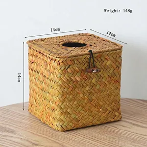 Detail of square hand-woven straw tissue box with wood button closure on wooden table