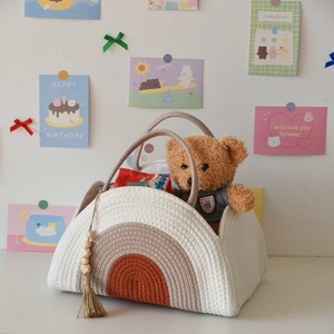 Detail of woven cotton rope diaper basket with rainbow pattern and decorative tassel