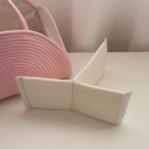 Detail view of pink cotton rope baby diaper caddy with adjustable cream dividers