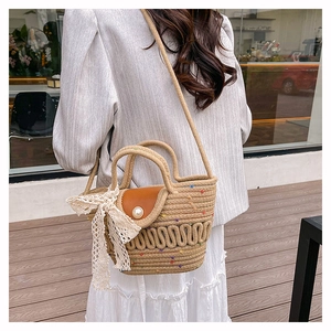 Détail du sac en paille avec nœud en dentelle blanche et rabat en cuir marron chic