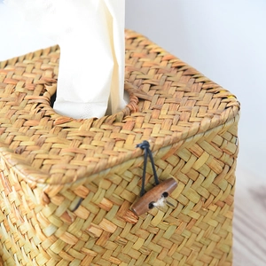 Detail view of handmade woven square tissue box with wood button and natural straw fiber texture