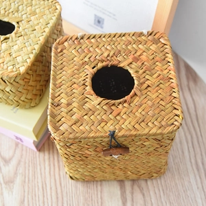 Detailed view of hand-woven straw tissue box featuring a wooden button closure and rustic texture