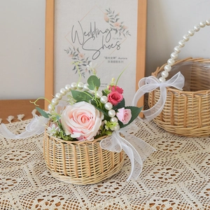 Detail of hand-woven flower basket with pearl handle and white chiffon ribbon bows
