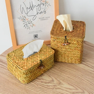 Detail of hand-woven straw tissue box featuring natural fiber texture and wood button closure