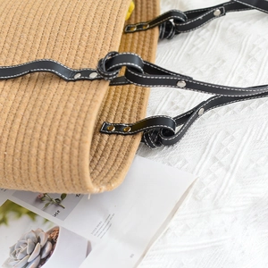 Close-up of woven tote bag strap with silver rivets and leather knot detail