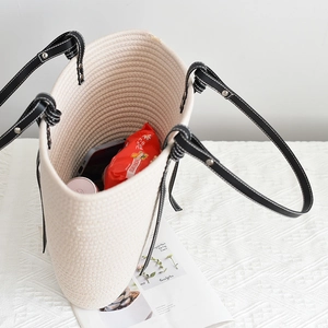 Detail of woven tote bag showing thick cotton rope texture and black leather handles
