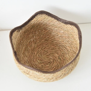 Detail of hand-woven plant fiber storage basket with brown fabric border and natural texture