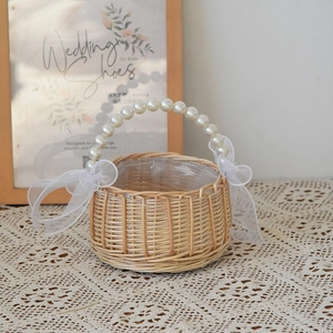 Detail of hand-woven wicker flower basket with pearl handle and white organza bows