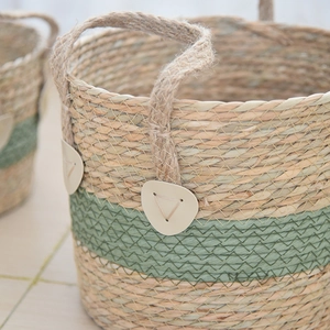 Close-up of woven seagrass basket showing two-tone green texture and reinforced handles