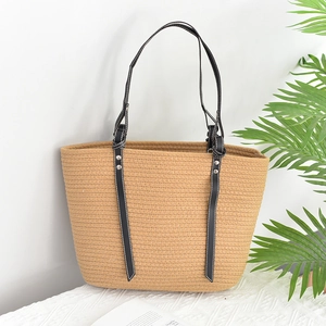 Large woven tote bag with black leather shoulder straps and stylish rivet details