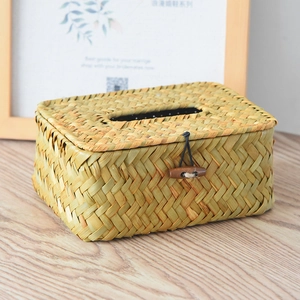 Detail of hand-woven straw tissue box with natural fiber texture and wooden toggle closure