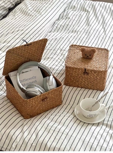 Detail of hand-woven seagrass storage boxes with a decorative plush bear on the lid