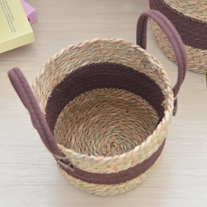 Detail of hand-woven straw plant basket featuring dark brown cotton handles and natural texture