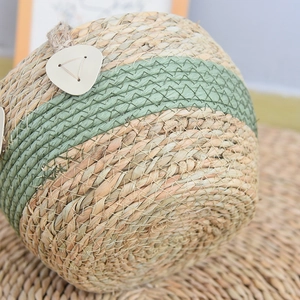 Detailed close-up of natural seagrass weave texture with green band and leather handle trim