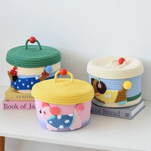 Detailed view of woven cotton rope storage baskets with cute dog embroidery and pom-poms