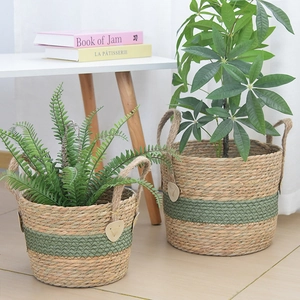 Detailed view of woven straw plant baskets with dual handles and green accent patterns