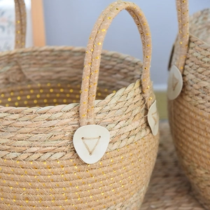 Detail of seagrass basket showing woven gold silk thread and leather handle attachment