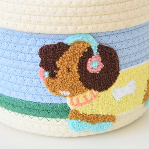 Detail of woven cotton storage basket featuring a cute embroidered puppy with blue headphones