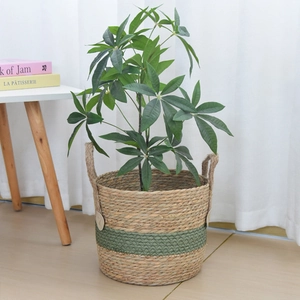Detail of woven straw plant pot with dual handles in natural and dark green design