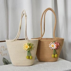 Dettaglio della borsa tote intrecciata con fiori fatti a mano e nappe a sfera verdi