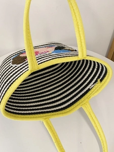 Close-up of woven tote bag with black stripes and yellow handles showing interior space