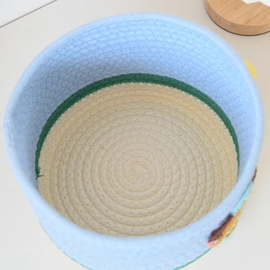 Top view of blue and white round cotton rope woven storage basket with decorative patches