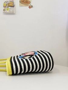 Close-up of woven bucket bag featuring striped pattern and colorful cartoon patch detail