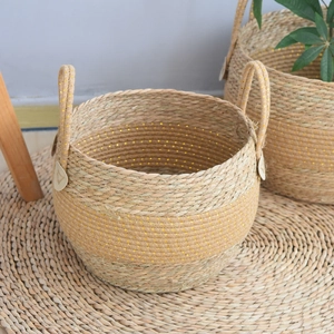 Detail of seagrass woven baskets with gold sequins and handles for plant storage