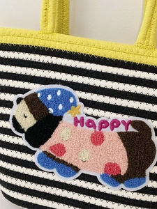 Detail of hand-woven tote bag with black-white stripes and cute dog plush embroidery